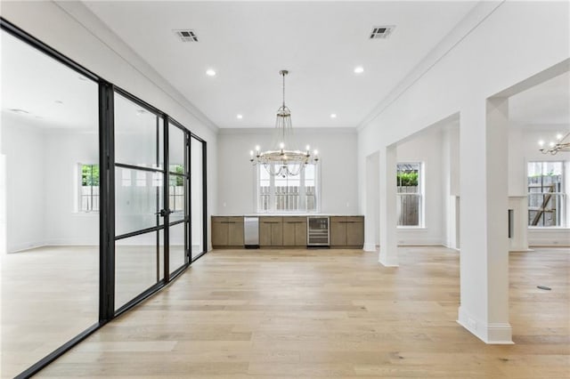 unfurnished dining area featuring an inviting chandelier, ornamental molding, light hardwood / wood-style floors, and wine cooler