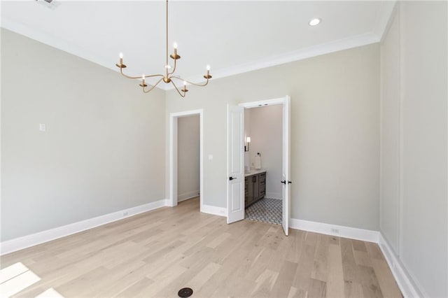 spare room with an inviting chandelier, light hardwood / wood-style flooring, and ornamental molding