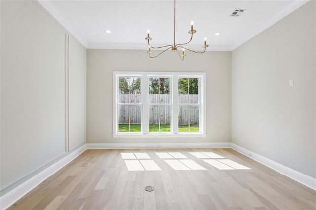 unfurnished room featuring an inviting chandelier, ornamental molding, and light wood-type flooring