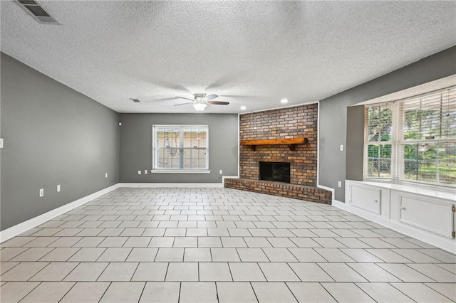 unfurnished living room with a brick fireplace, light tile patterned flooring, ceiling fan, and a healthy amount of sunlight