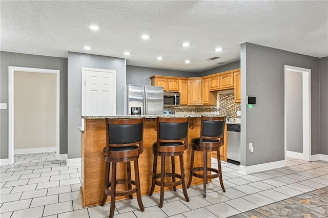 kitchen with light tile patterned flooring, decorative backsplash, stainless steel appliances, and a breakfast bar area