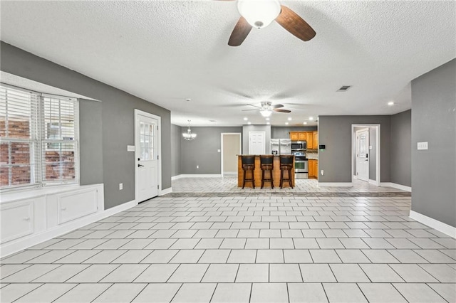 unfurnished living room with light tile patterned flooring, a textured ceiling, and ceiling fan