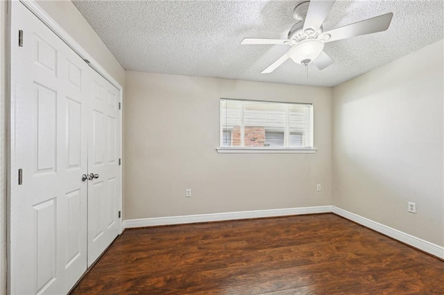 unfurnished bedroom with ceiling fan, dark wood-type flooring, a textured ceiling, and a closet