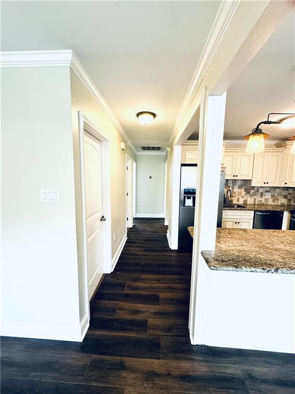 corridor featuring sink, ornamental molding, and dark hardwood / wood-style flooring