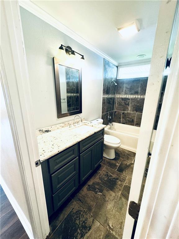 full bathroom with toilet, tile patterned floors, tiled shower / bath combo, ornamental molding, and vanity