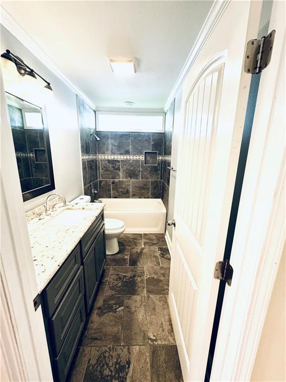 full bathroom with crown molding, toilet, tile patterned floors, tiled shower / bath combo, and vanity