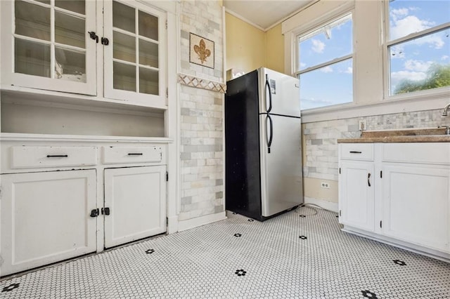 kitchen featuring crown molding, stainless steel fridge, white cabinetry, and sink