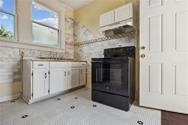 kitchen featuring light tile patterned floors, a wealth of natural light, electric range, and white cabinets