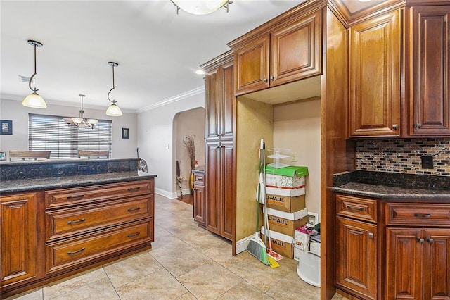 kitchen featuring a chandelier, hanging light fixtures, decorative backsplash, ornamental molding, and dark stone countertops