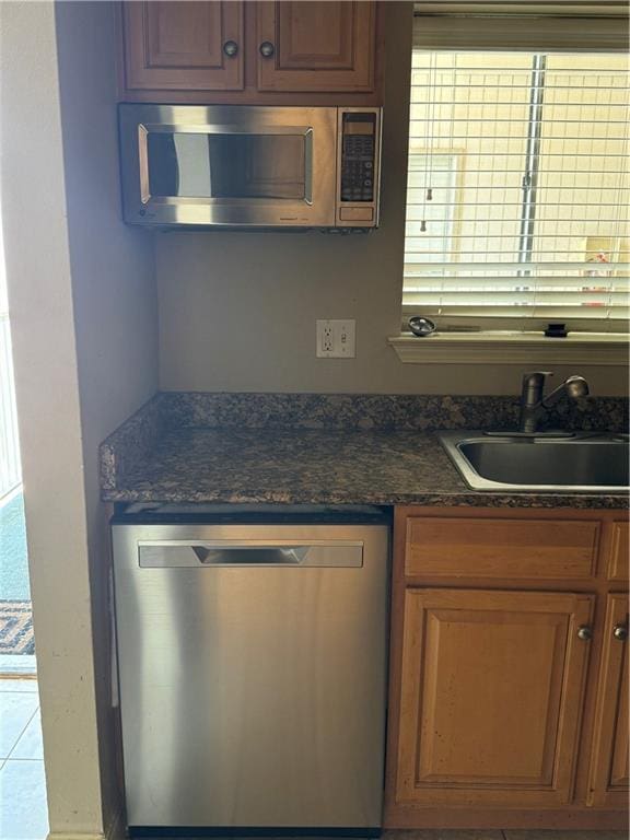 kitchen featuring stainless steel appliances, sink, and dark stone counters