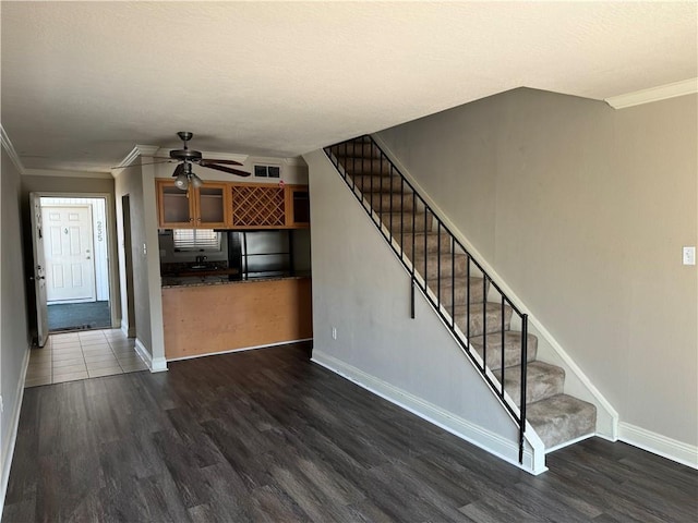 unfurnished living room with dark hardwood / wood-style flooring, crown molding, and ceiling fan