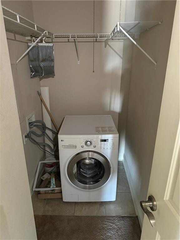 washroom featuring washer / dryer and dark tile patterned flooring