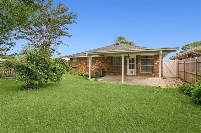 rear view of property featuring ceiling fan, cooling unit, a patio area, and a lawn