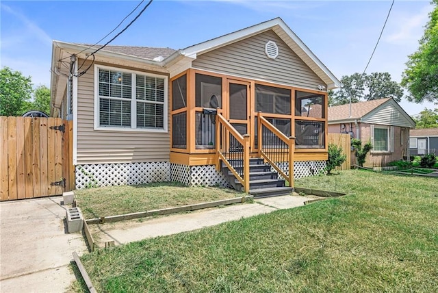 rear view of property with a sunroom and a lawn