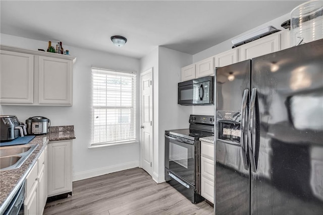 kitchen featuring black appliances, sink, white cabinetry, and light hardwood / wood-style floors