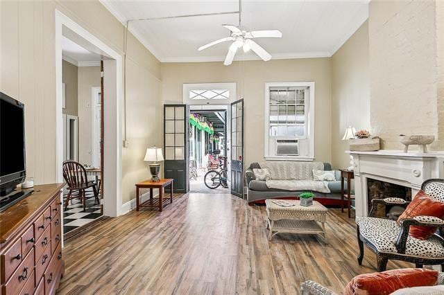 living room featuring ceiling fan, cooling unit, ornamental molding, wood-type flooring, and a premium fireplace