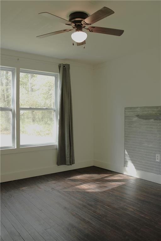 spare room featuring baseboards, wood finished floors, and a ceiling fan