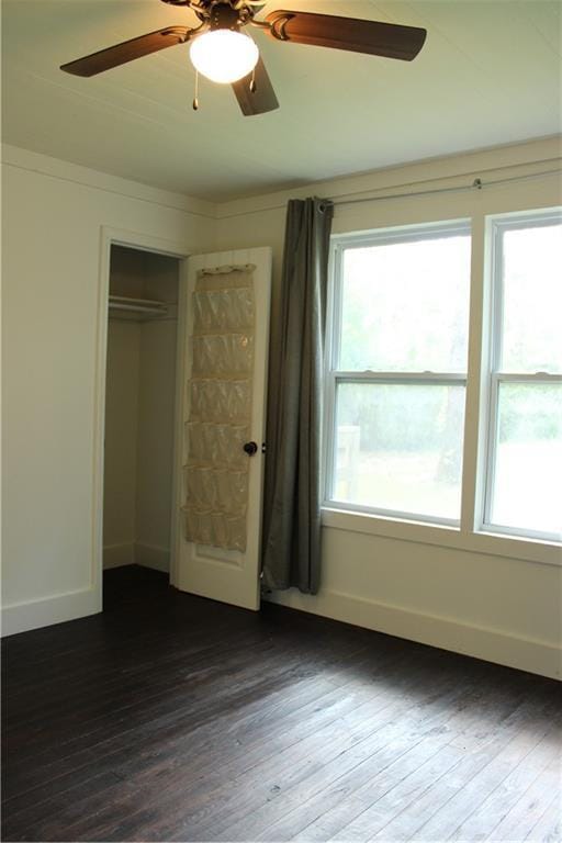 unfurnished bedroom with ceiling fan, a closet, baseboards, and dark wood finished floors