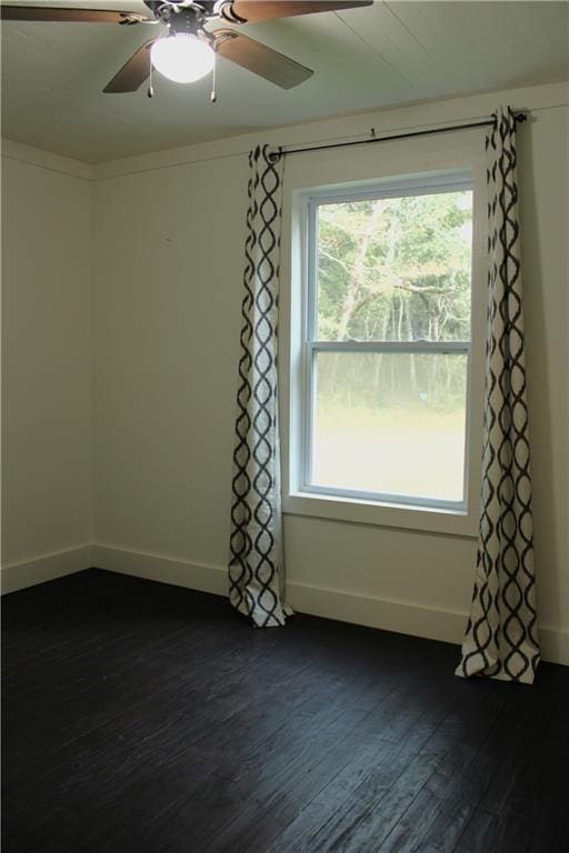 empty room with ceiling fan, dark wood-type flooring, and baseboards