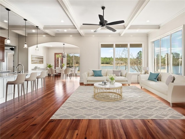 living room featuring ceiling fan with notable chandelier, coffered ceiling, and wood-type flooring