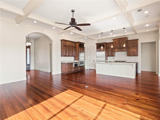 unfurnished living room with beam ceiling, coffered ceiling, ceiling fan with notable chandelier, and hardwood / wood-style flooring