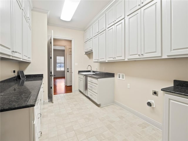 interior space featuring hookup for an electric dryer, cabinets, crown molding, light wood-type flooring, and sink