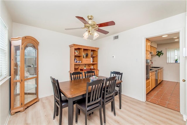 dining room featuring light wood-type flooring, sink, and ceiling fan