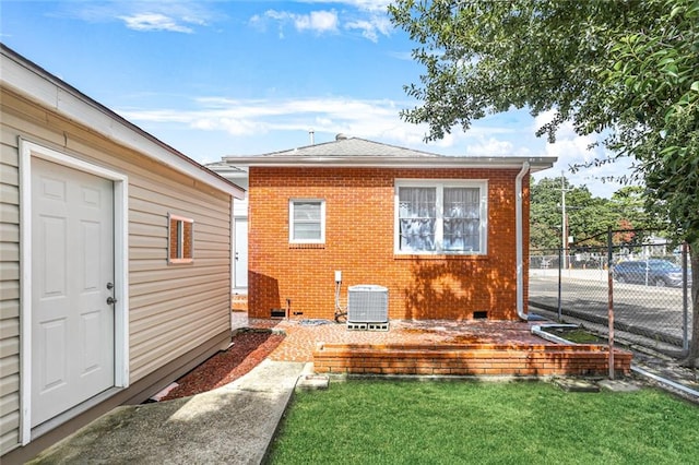 back of house with central AC unit and a lawn