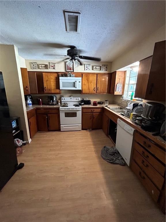 kitchen with a textured ceiling, ceiling fan, light wood-type flooring, white appliances, and sink