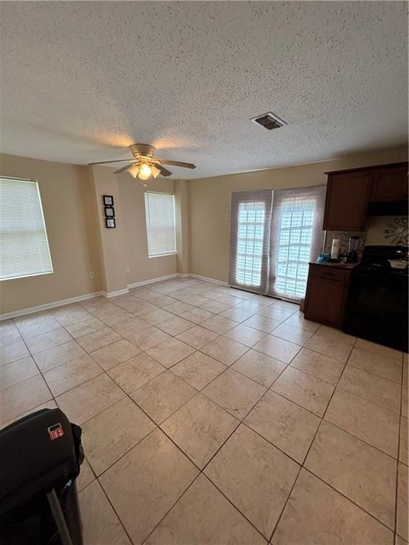 unfurnished living room with ceiling fan, light tile patterned floors, and a textured ceiling