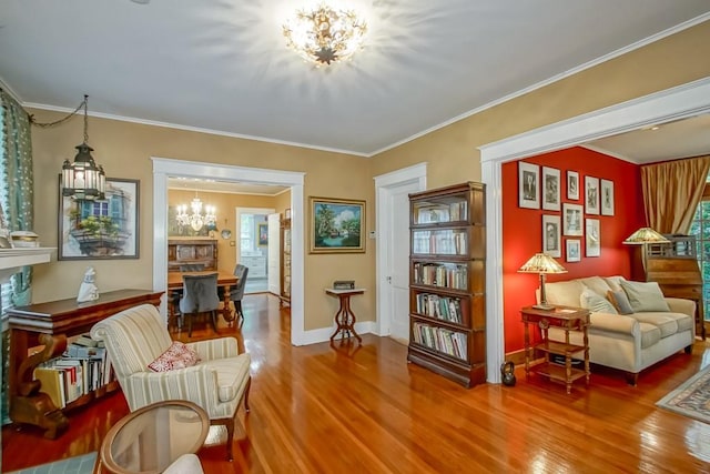 living area with hardwood / wood-style floors, ornamental molding, and a chandelier