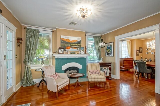 living area featuring hardwood / wood-style floors, ornamental molding, and a notable chandelier