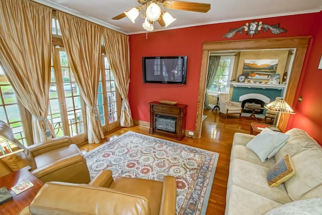 living room featuring hardwood / wood-style flooring, ornamental molding, plenty of natural light, and ceiling fan