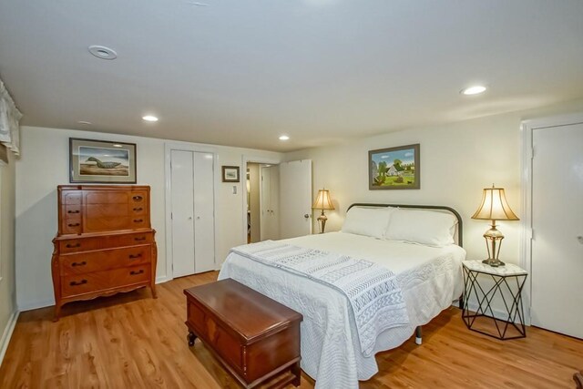 bedroom with light wood-type flooring and two closets