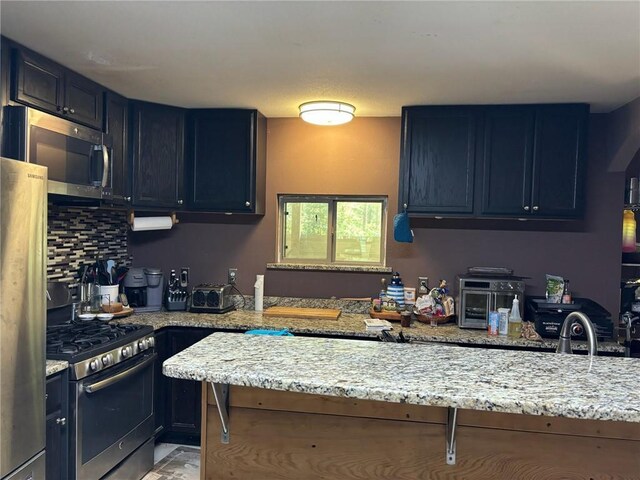 84653 Camus Ln, Covington, LA 70435 - kitchen with blue cabinets, decorative backsplash, light stone counters, and stainless steel appliances