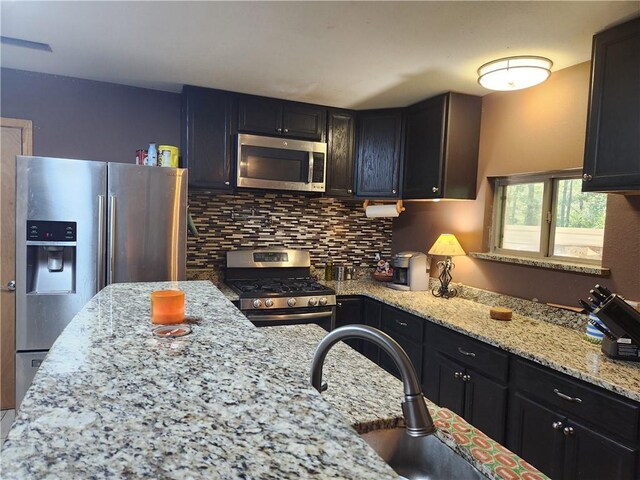 kitchen with appliances with stainless steel finishes, backsplash, and light stone counters