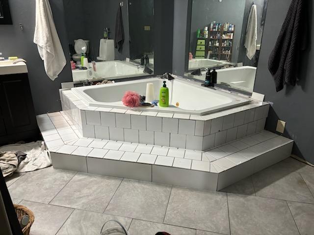 bathroom with vanity and a relaxing tiled tub