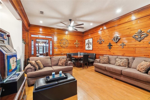 living room featuring light hardwood / wood-style flooring, wooden walls, and ceiling fan