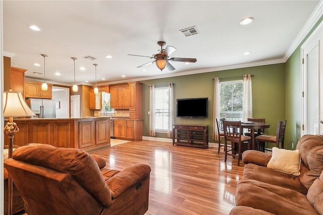 living room featuring light wood-type flooring, ornamental molding, and ceiling fan