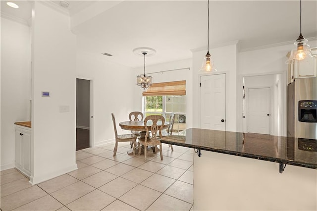 tiled dining area featuring ornamental molding and an inviting chandelier