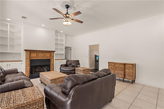 tiled living room with built in shelves, ceiling fan, and crown molding