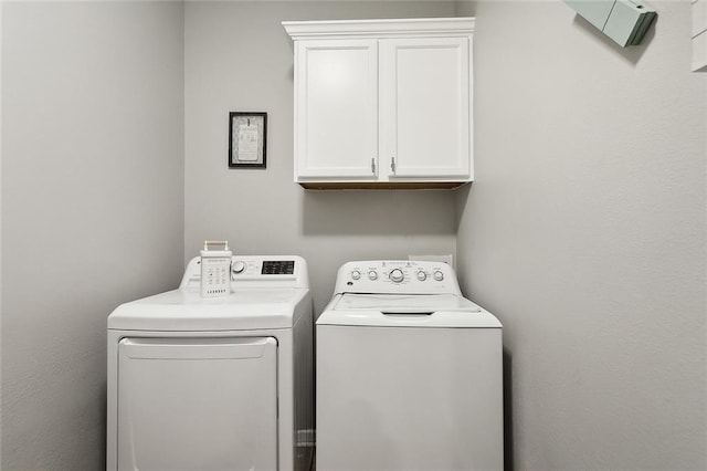 clothes washing area with cabinets and washer and clothes dryer