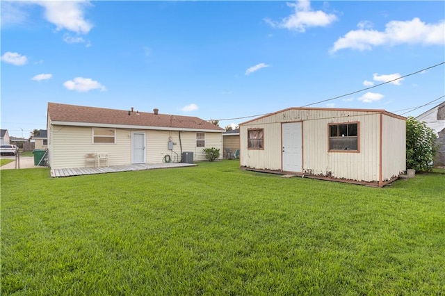 rear view of property with a lawn and a storage unit