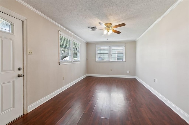 empty room with dark wood-style floors, baseboards, visible vents, and ornamental molding