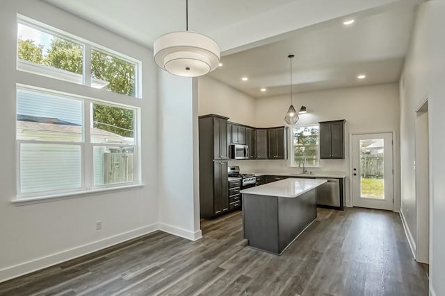 kitchen featuring sink, appliances with stainless steel finishes, dark hardwood / wood-style floors, a center island, and decorative light fixtures