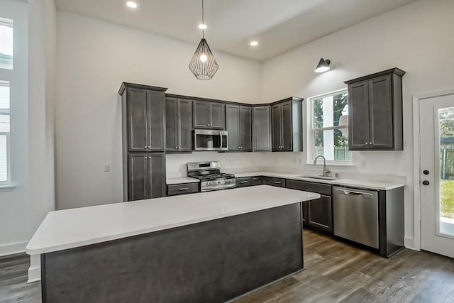 kitchen featuring a kitchen island, dark hardwood / wood-style floors, pendant lighting, sink, and stainless steel appliances