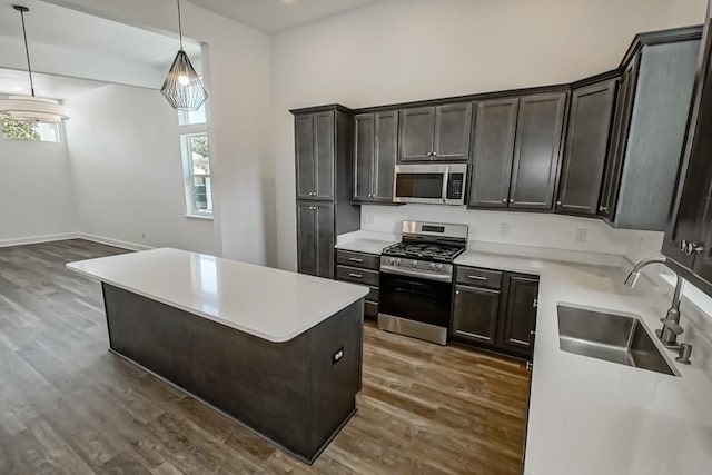 kitchen featuring appliances with stainless steel finishes, sink, hardwood / wood-style flooring, decorative light fixtures, and a kitchen island