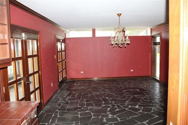 unfurnished room featuring french doors and an inviting chandelier