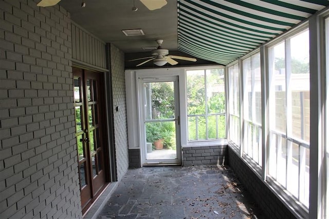 unfurnished sunroom with ceiling fan