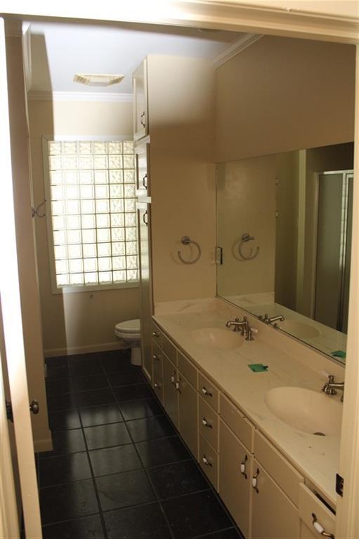 bathroom featuring dual bowl vanity, ornamental molding, tile patterned floors, and toilet